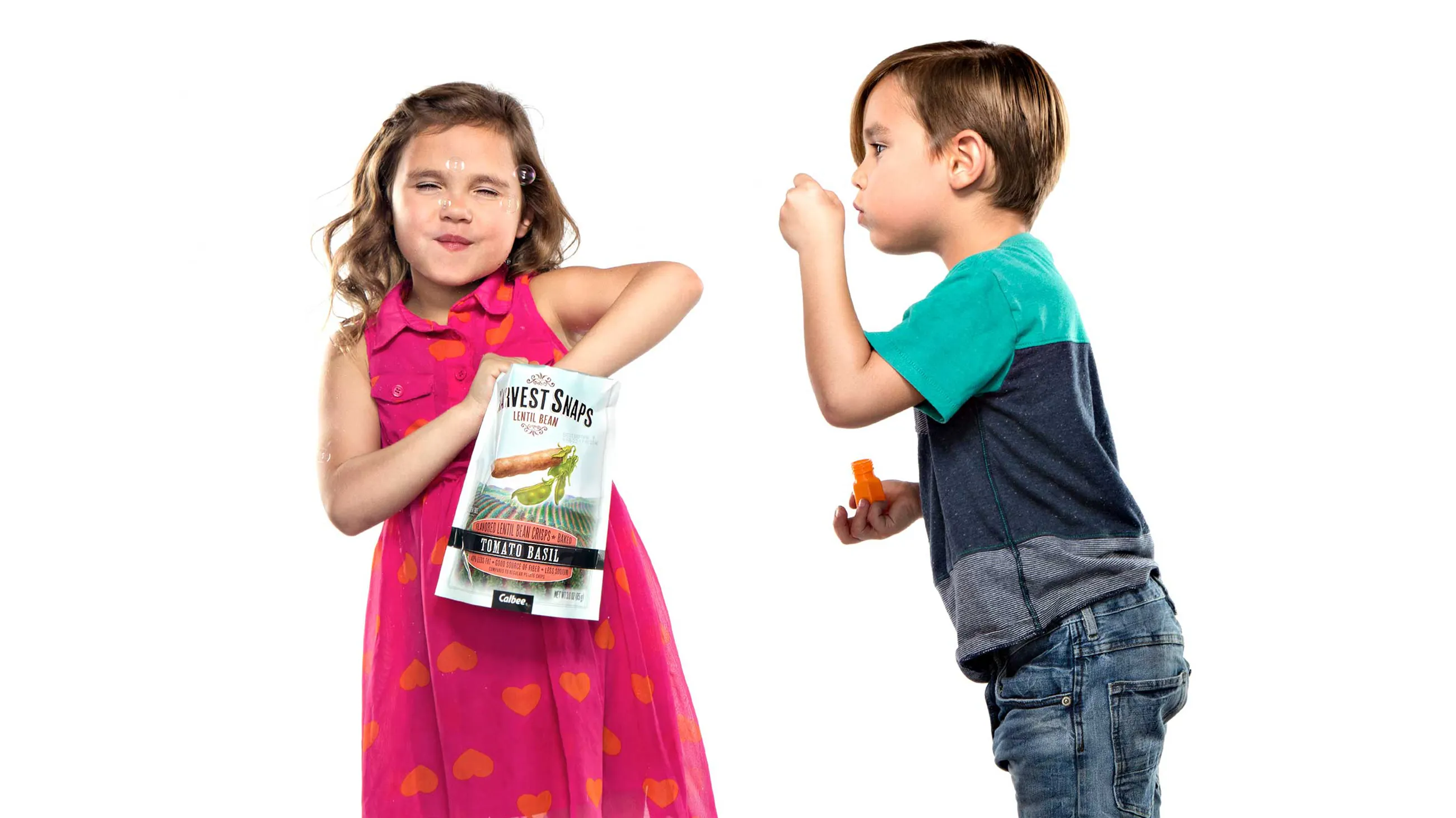 Two kids eating Harvest Snaps and blowing bubbles